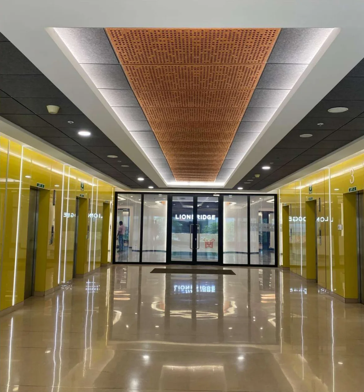 Office lobby with a timber ceiling feature, glass walls and a reflective stone floor