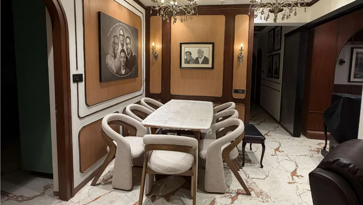Residential dining space with upholstered chairs, a stone table and paneled walls